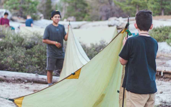 two students work together to set up a shelter on an outward bound course